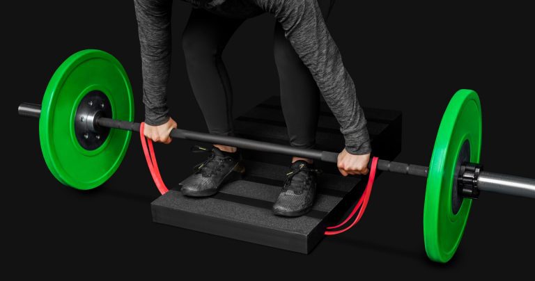 close up of a woman performing a banded deficit deadlift on a step board