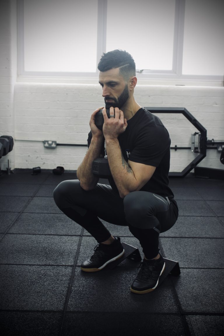 Man in a gym performing a goblet squat on the forte fitness slant blocks