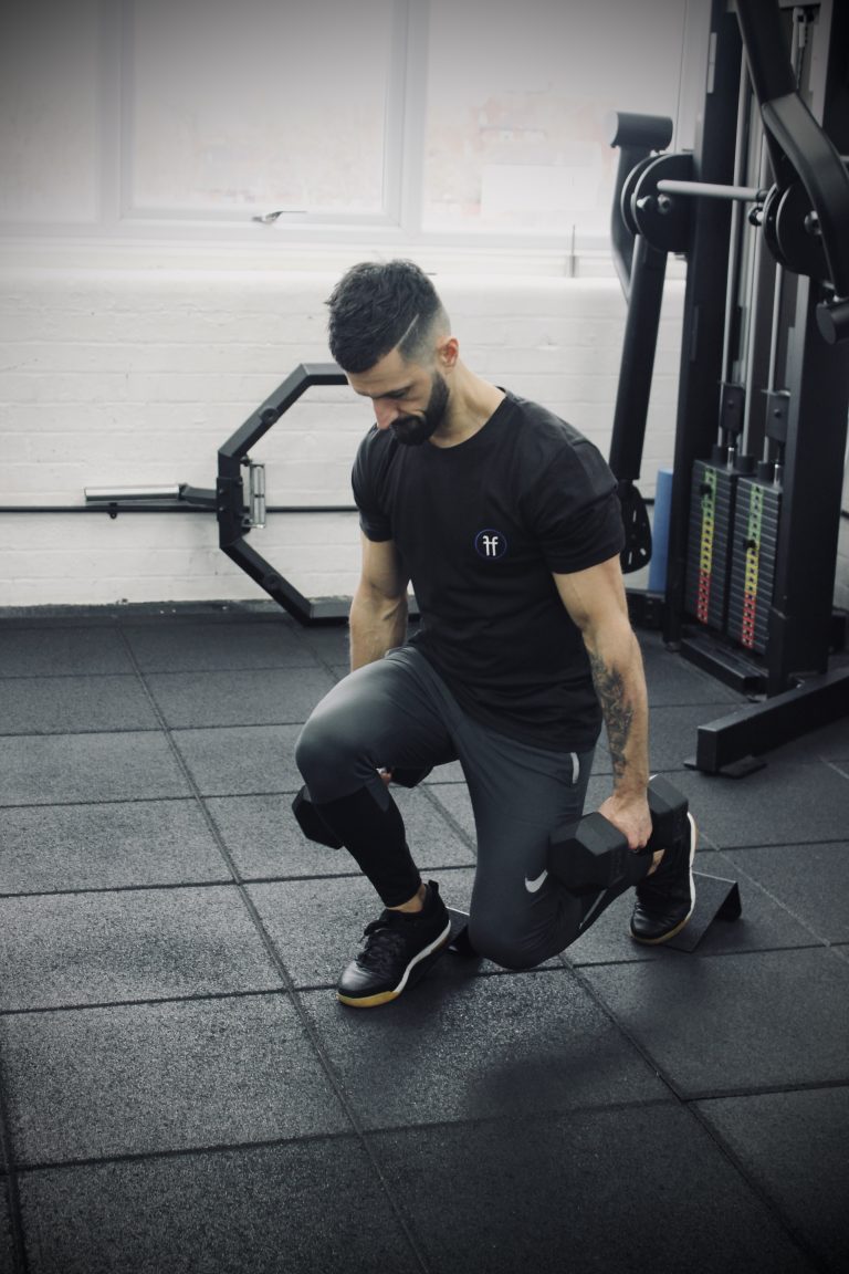 Man in a gym performing dumbbell split squats using he forte fitness slant blocks