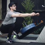 man performing a belt squat with the forte fitness belt squat attachment with 2 blue 20kg plates, on an outdoor rig surrounded by trees