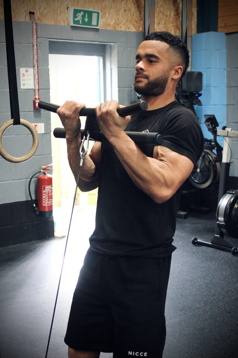 A man using the Forte Fitness curl bar from a front-facing angle. Tension in the arm muscles as the bar and cord are pulled towards his chin.