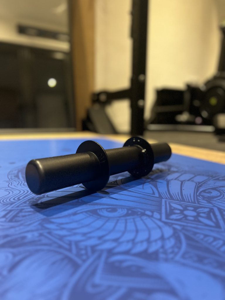 A Forte Fitness Axle Dumbbell bar without weights attached placed on a blue floor.