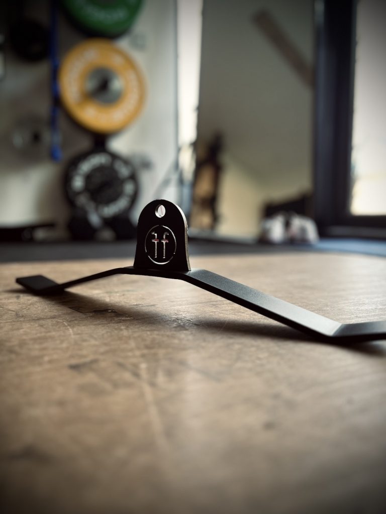 A Forte Fitness pushdown device placed on a gym floor. The light shines through the Forte Fitness logo at the front of the product.