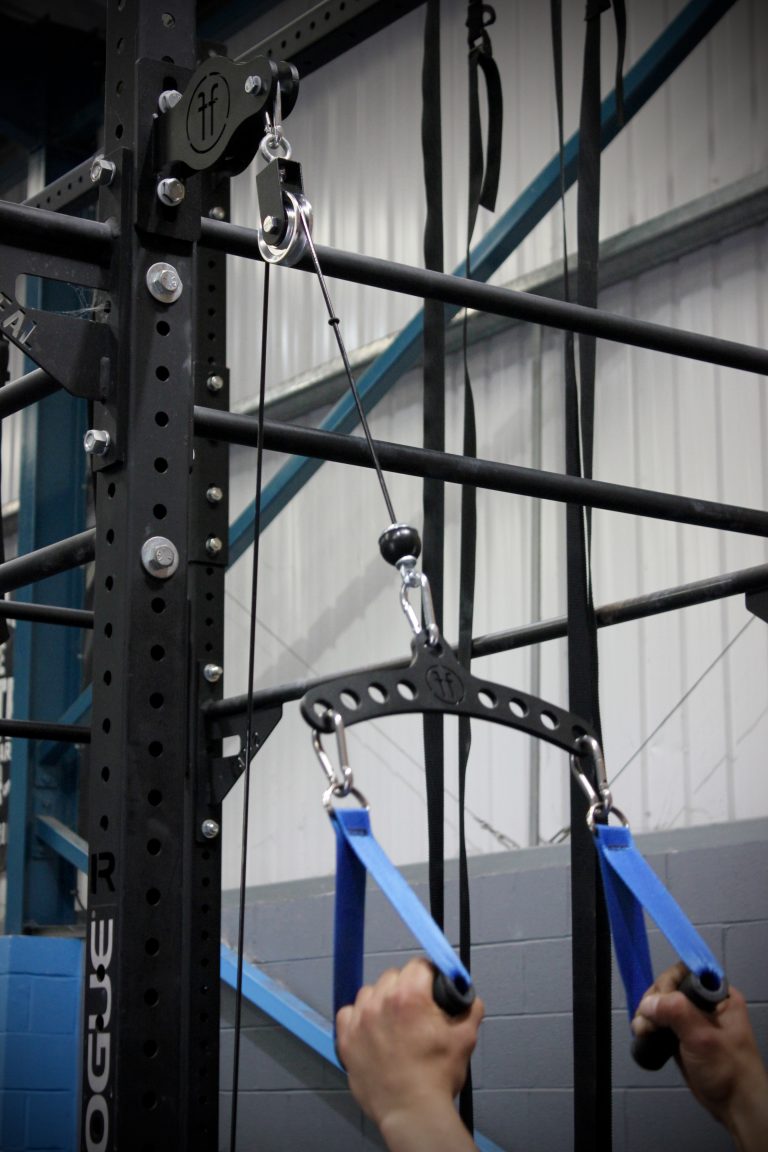 A black steel multibar machine with the Forte Fitness logo placed at the top. Blue grip handles with someone pulling in a downward motion.