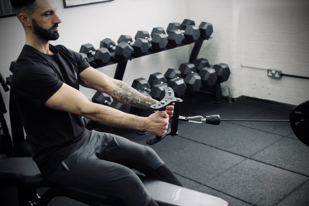 Man in a bodybuilding gym performing a cable row movement using the Forte Fitness cable row attachment