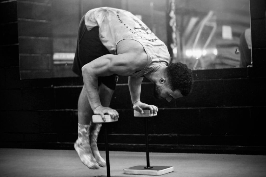 black and white photo of man doing a press to handstand on canes