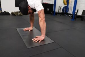 man performing a handstand in a gym using a handstand mat