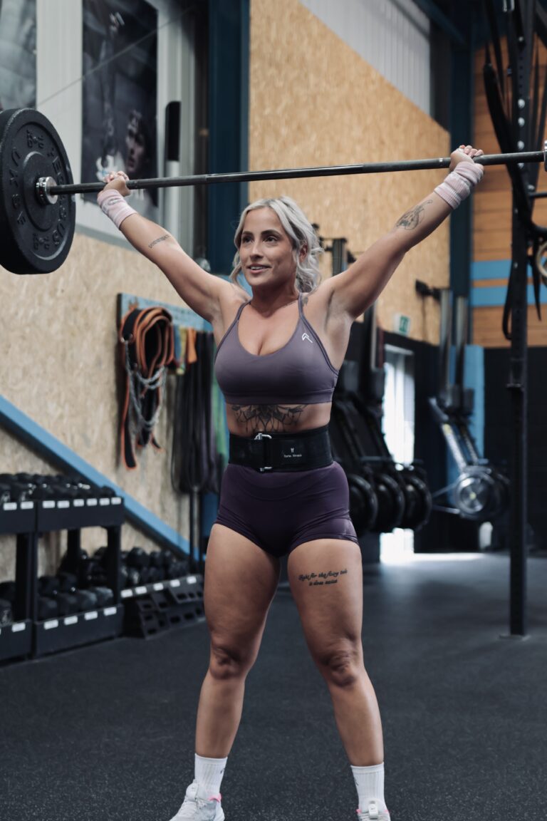 woman performing a snatch weightlifting movement wearing a hybrid lifting belt