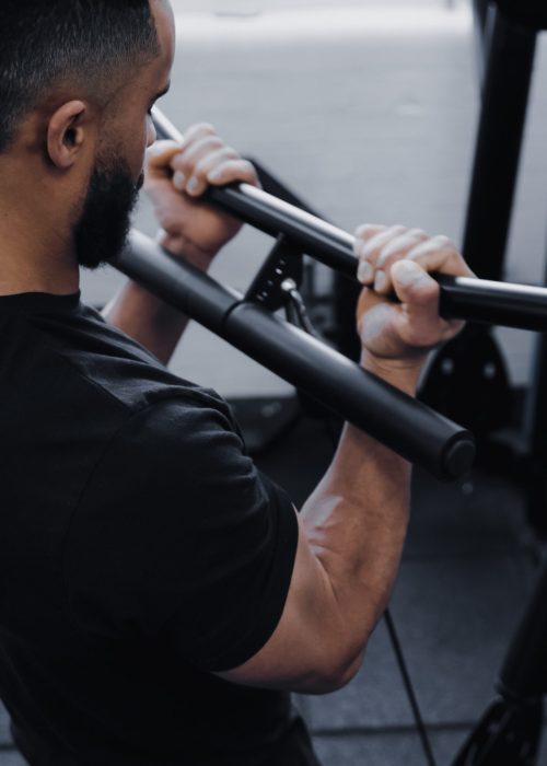 A man using the Forte Fitness black curl bar in a gym.