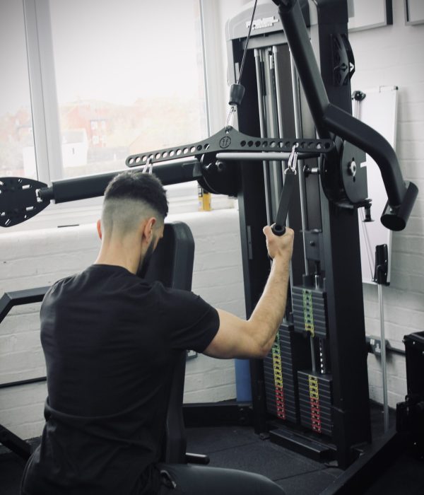 man doing a lat pulldown in a gym